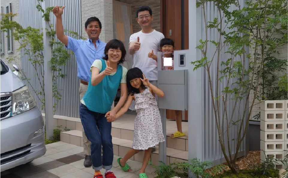 自宅の前で写真を撮る家族の様子