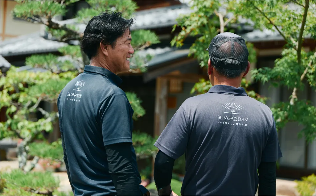 庭で男性2人が会話をする様子