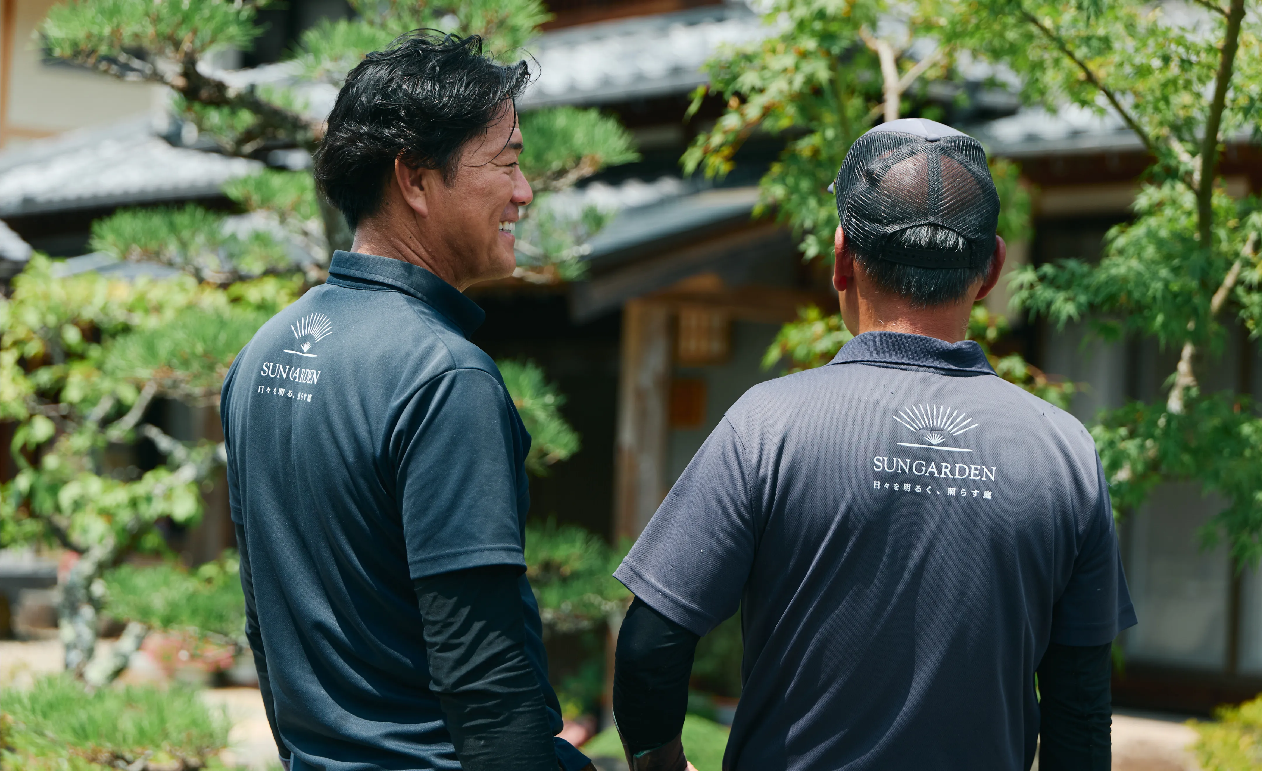 庭で男性2人が会話をする様子